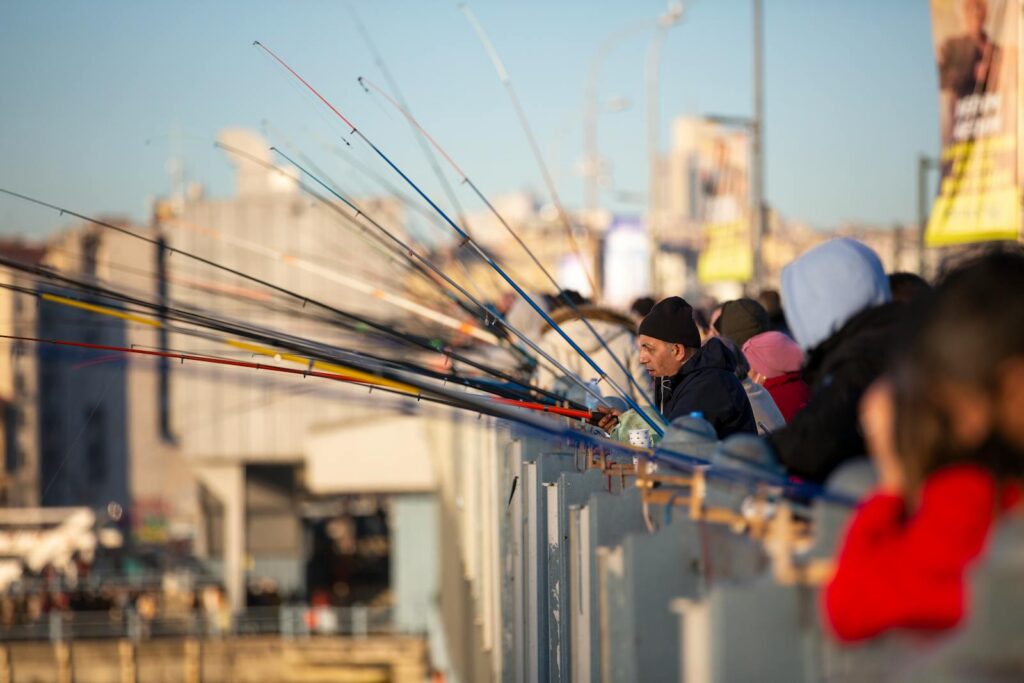 People engaged in fishing on a city bridge, casting rods into the water below.