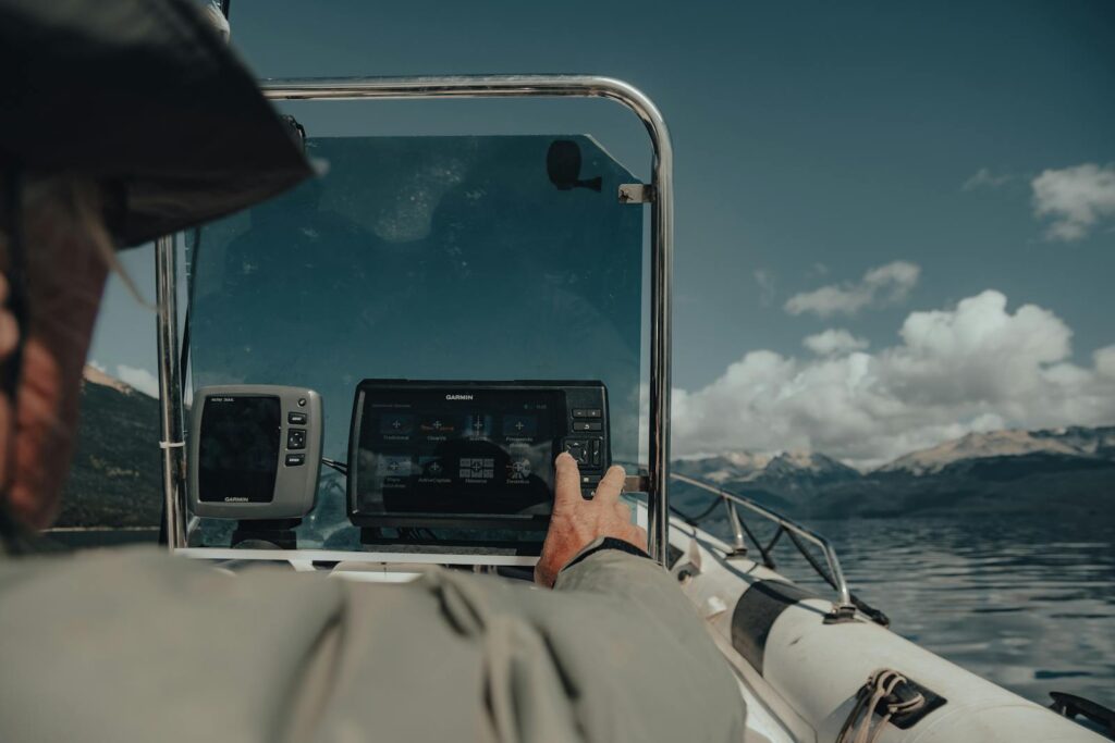 Man steering motorboat using GPS on a scenic lake with mountain backdrop