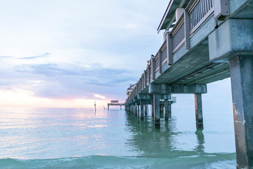 Stunning sunset at Clearwater Beach Pier with calm ocean waters and pastel skies.