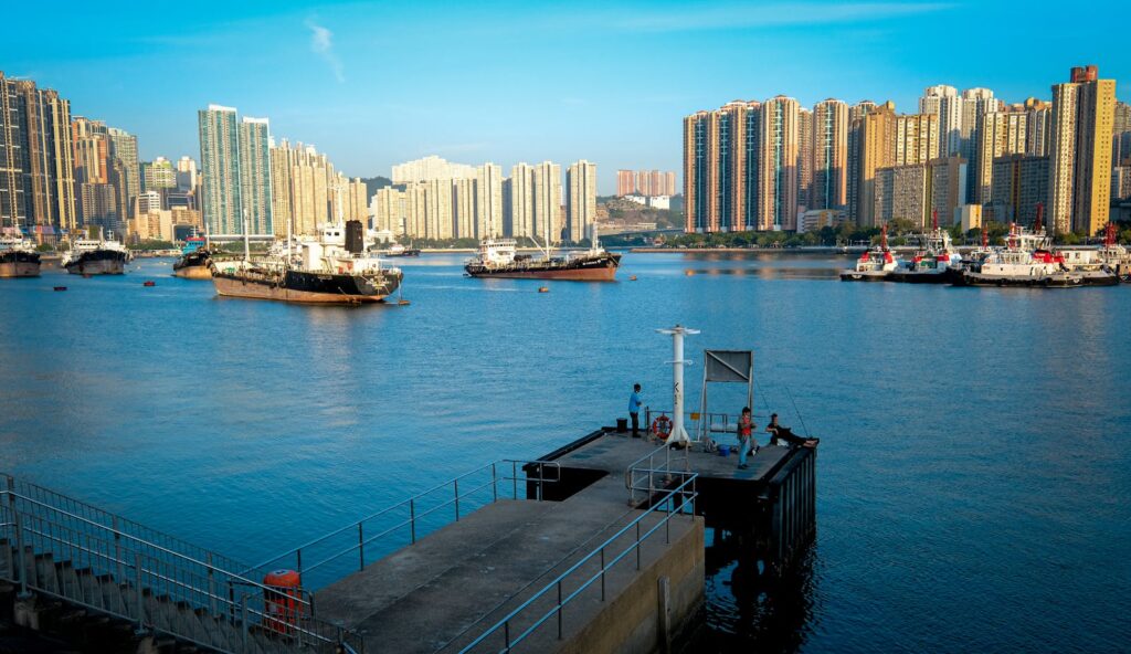 Scenic view of Hong Kong's bustling harbor with skyscrapers and boats under a clear sky.