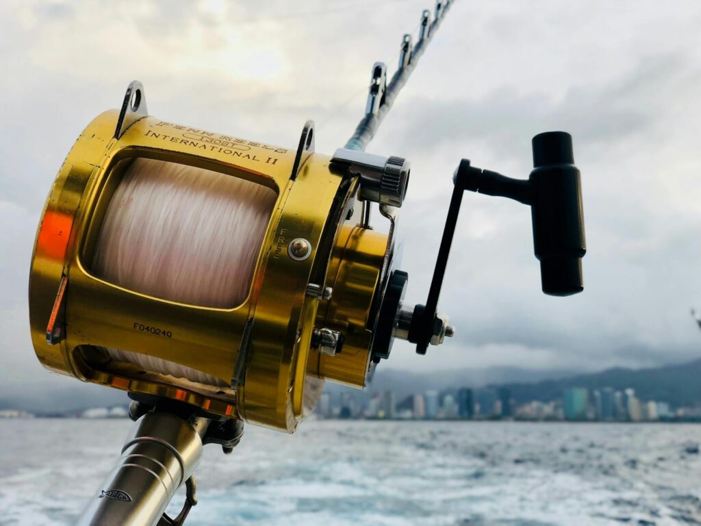 Close-up of a fishing rod and reel over the ocean with the Honolulu skyline in the background.