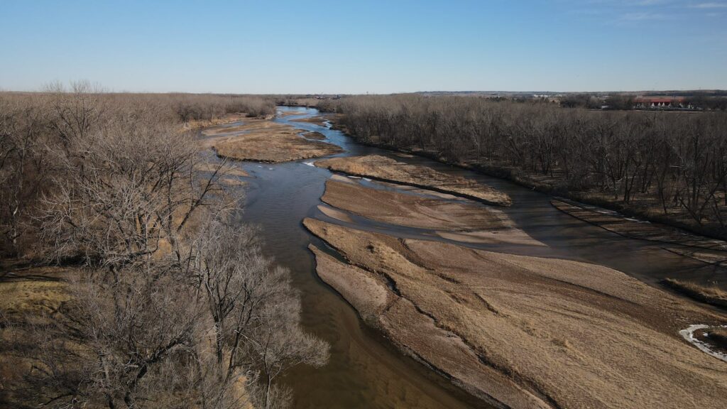 Aerial view of winding North Platte River with sandbanks in a sunlit winter landscape.