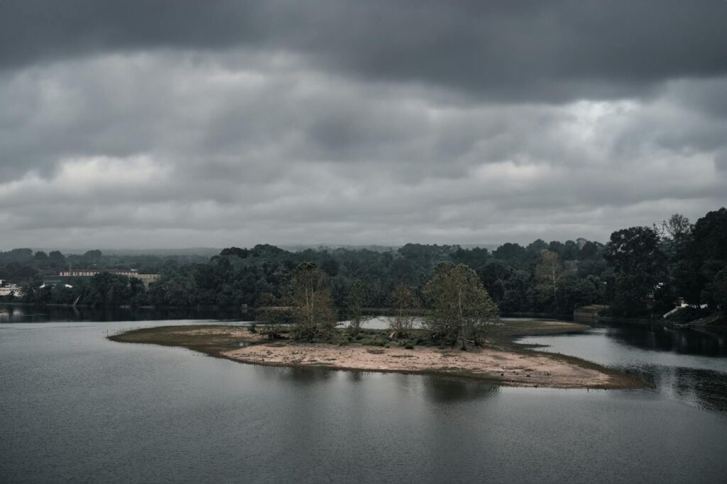 A serene river scene with an island and moody overcast clouds, perfect for nature enthusiasts.