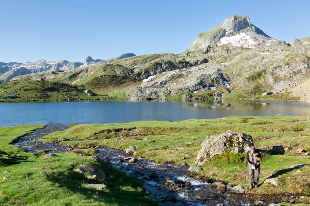 Fisherman enjoys a serene day by a mountain lake in the Pyrenees.