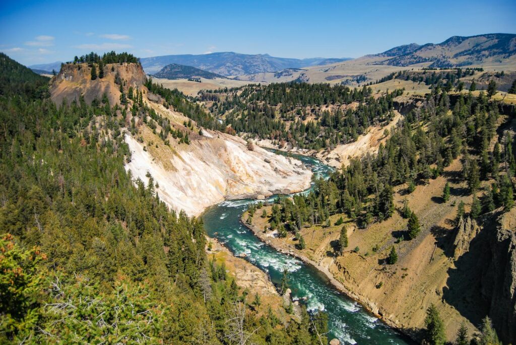 Breathtaking view of a canyon river in Yellowstone National Park under a blue sky.