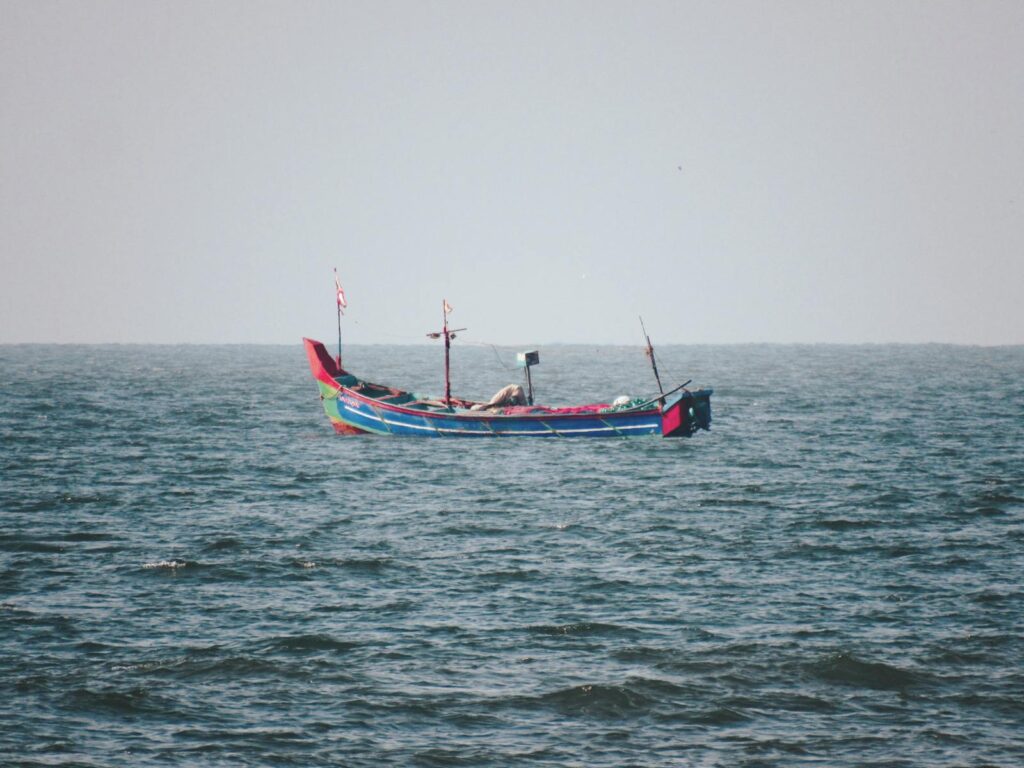 A colorful traditional boat floats serenely in the vast Arabian Sea, peaceful and solitary.