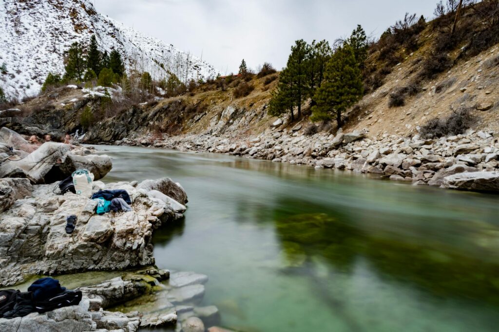 A beautiful river landscape showcasing flowing water, rocky banks, and snowy trees.