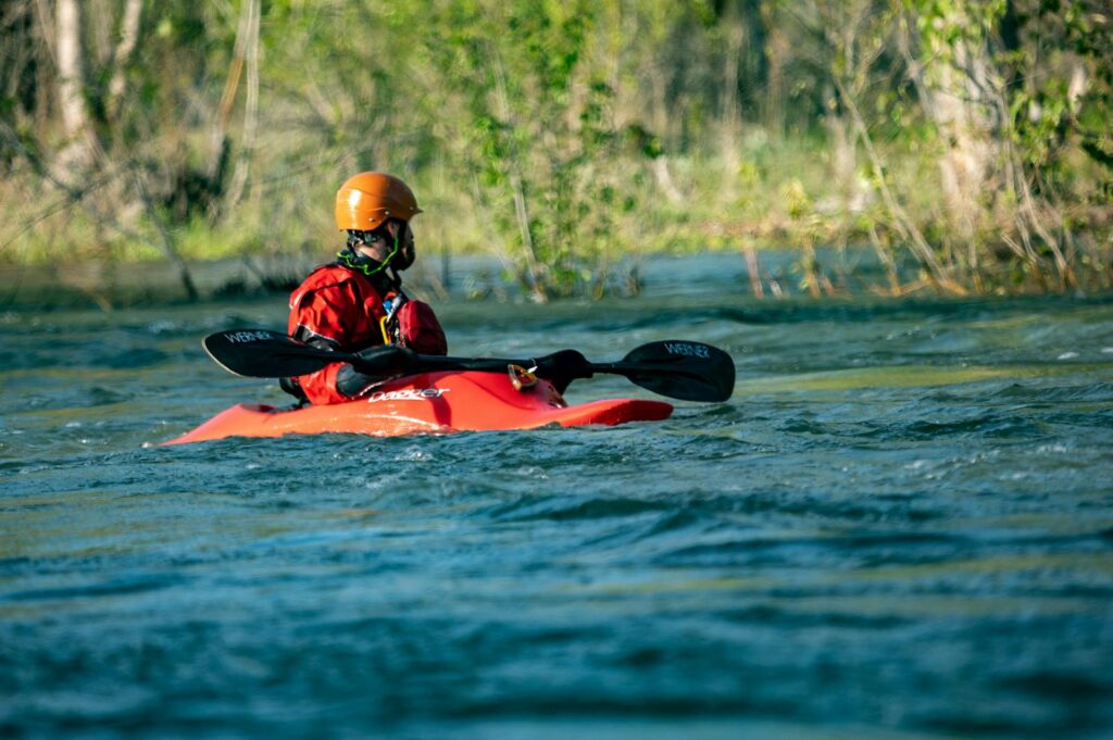 A man enjoys kayaking on a vibrant river, surrounded by nature.