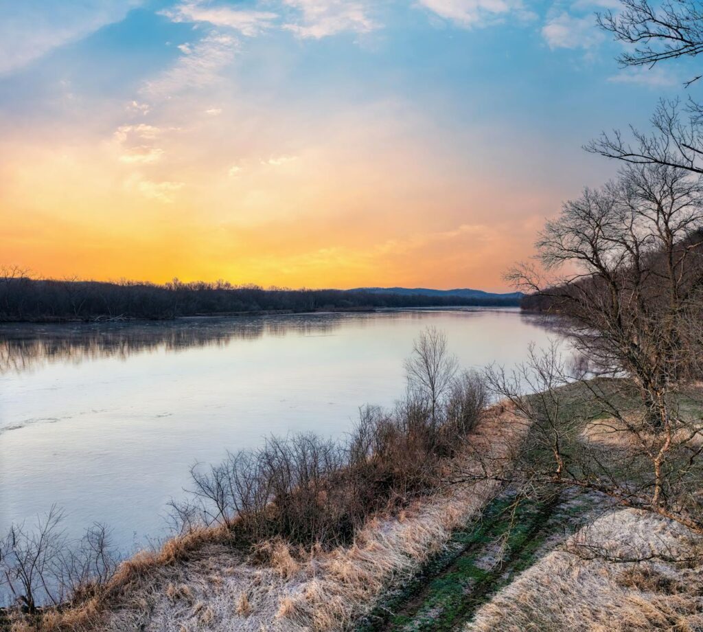 Serene winter sunset over a frozen river in Ella, Wisconsin.