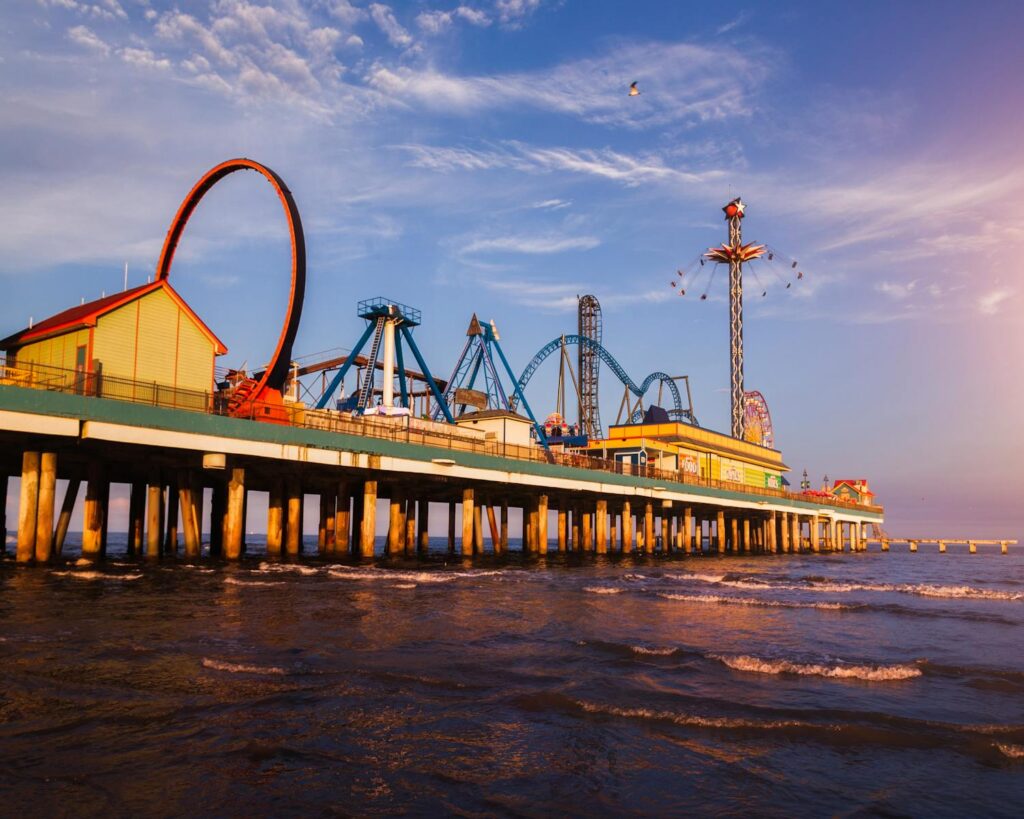 Vibrant sunset over Galveston's iconic amusement pier with thrilling rides and ocean waves.