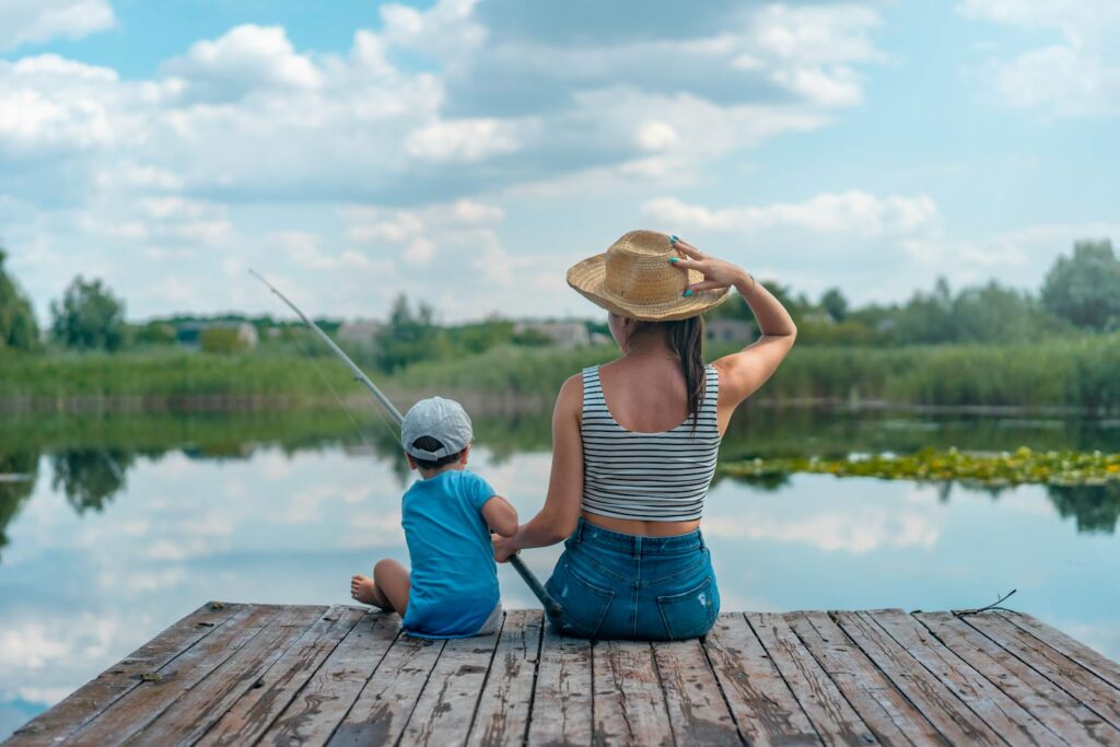 A mom and her child fishing on a peaceful wooden dock by a calm lake in Ukraine.