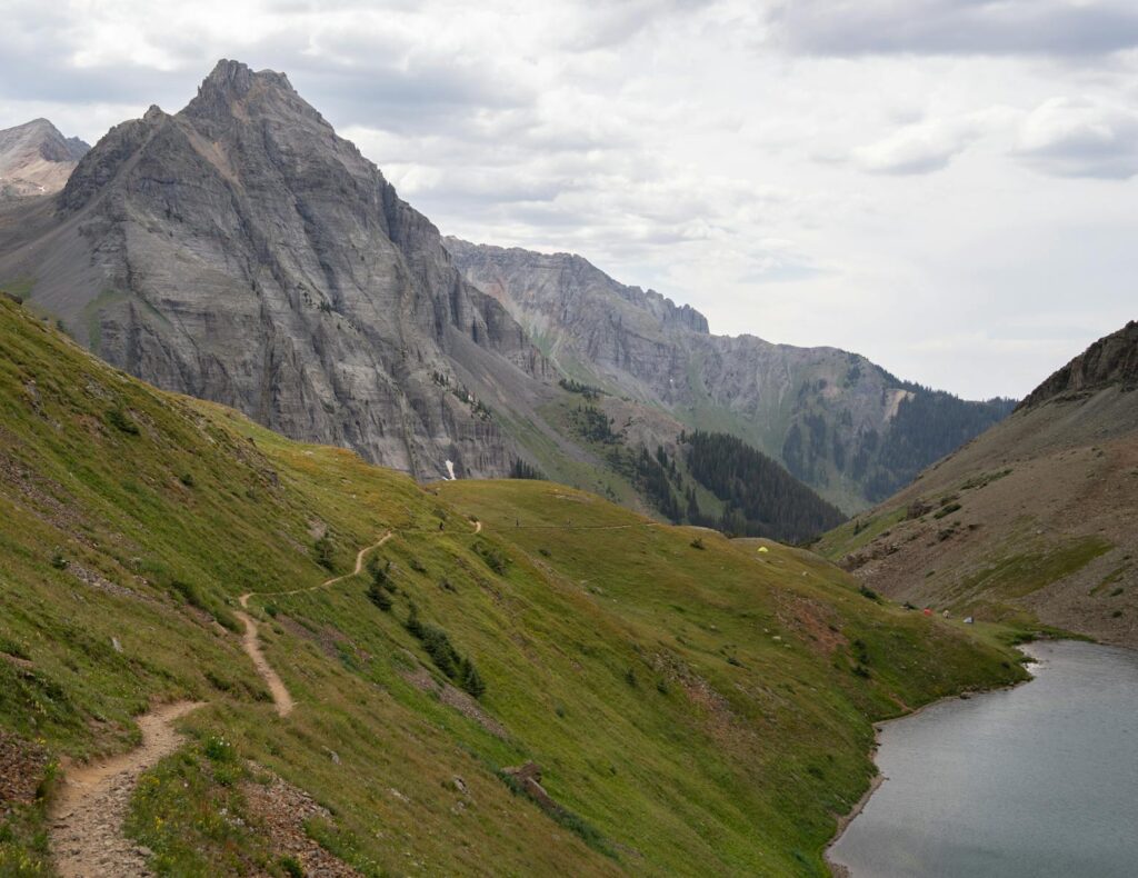Explore the breathtaking mountain trail leading to an alpine lake in Colorado's rugged landscape.
