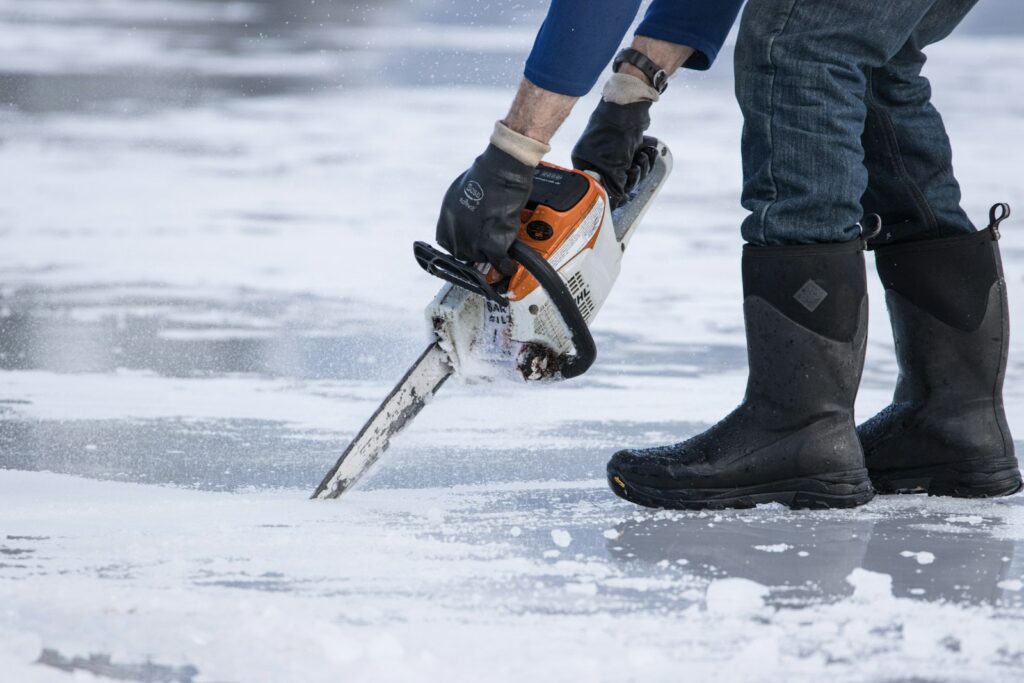 a man holding a chainsaw on top of ice
