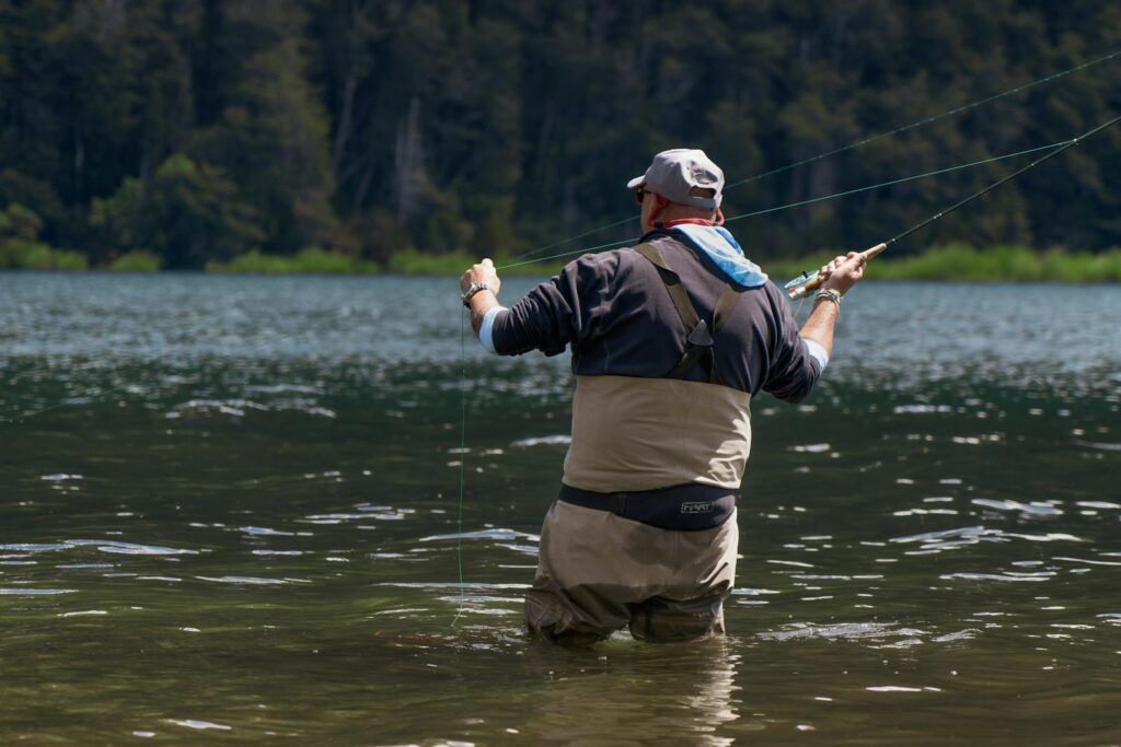 Man fly fishing in clear alpine lake in Patagonia, Argentina.