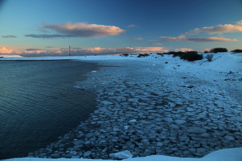 Serene winter scene of a frozen beach in Vadsø, Norway, captured at sunset.