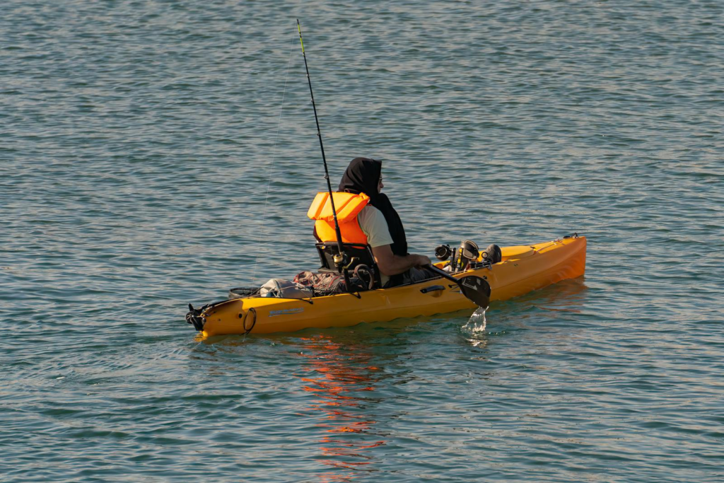 A man in a kayak fishing on a calm lake in Comunidad Valenciana, Spain.