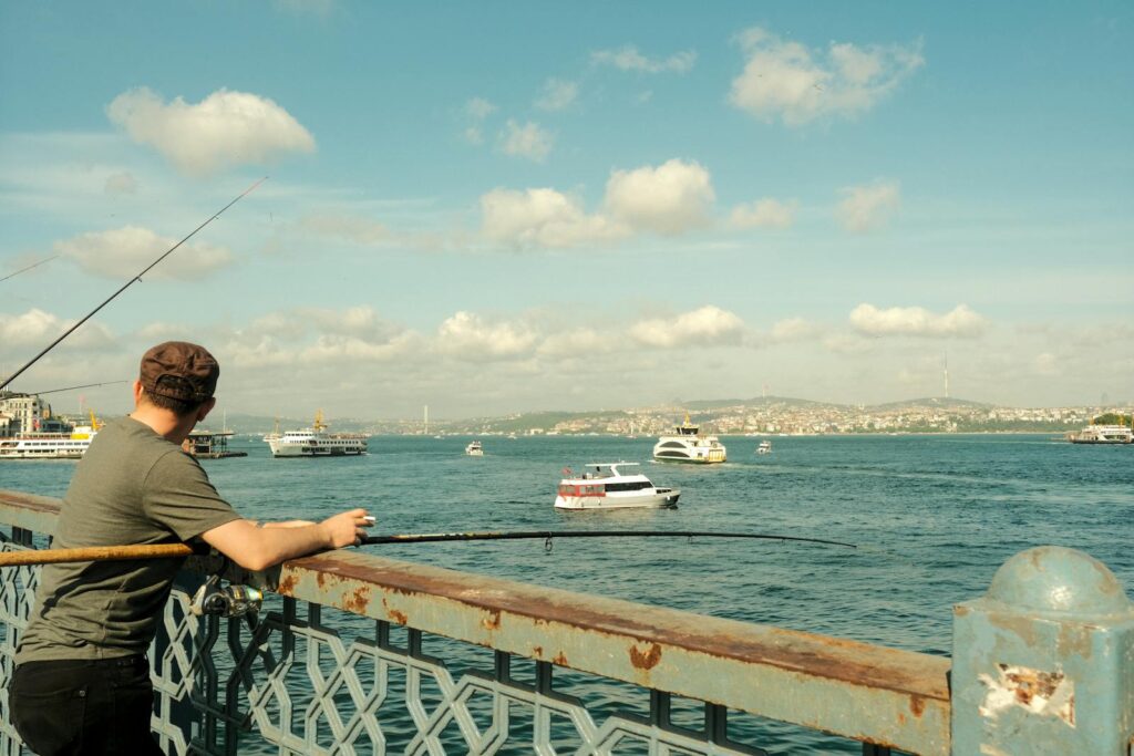 A fisherman enjoys a sunny day fishing from Galata Bridge over the Bosphorus in Istanbul.