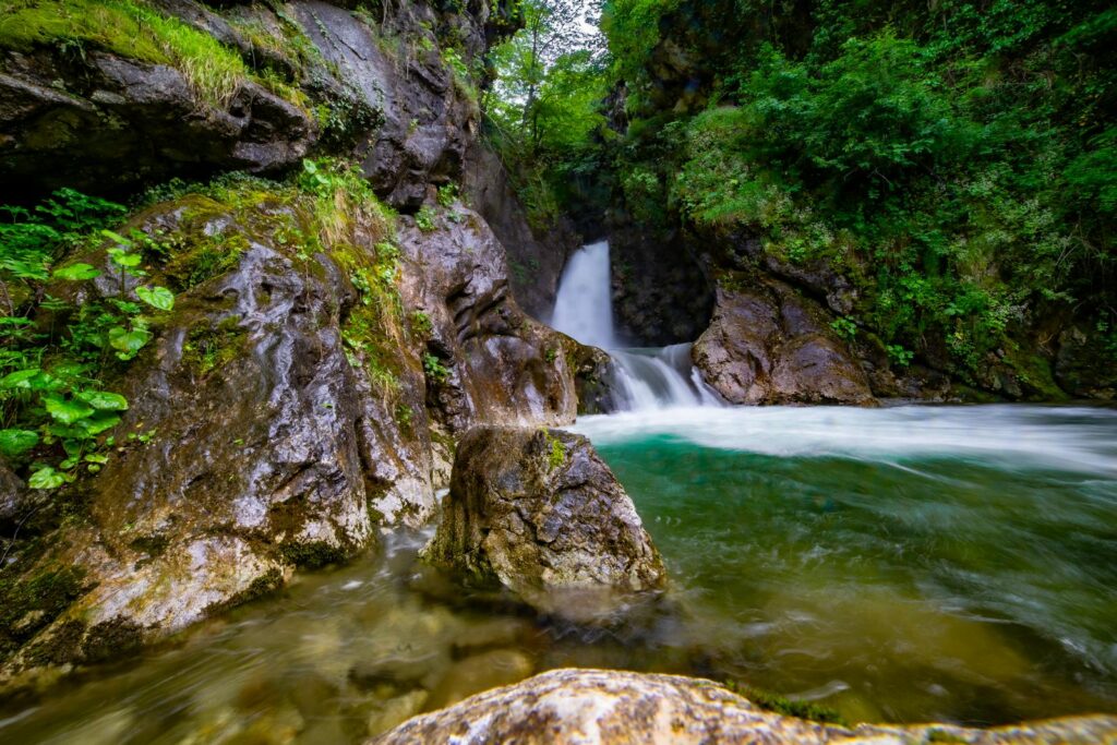 Beautiful waterfall surrounded by lush greenery and rocky canyon, captured in vibrant detail.