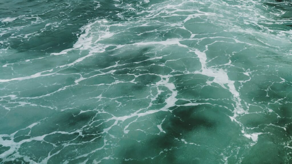Captivating aerial view of turquoise ocean waves and white surf texture, showcasing nature's beauty.