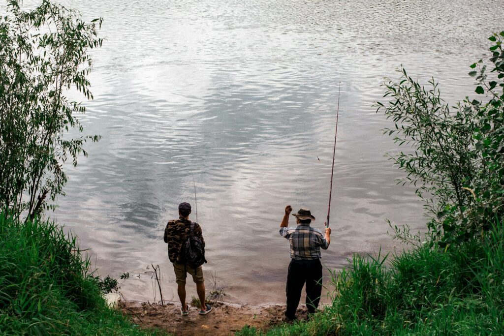 A couple of men standing next to a body of water