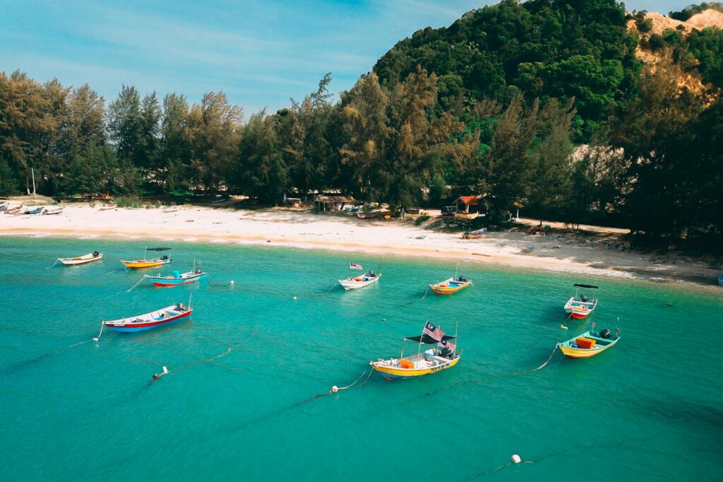 Vibrant boats moored on turquoise water along a serene tropical beach.