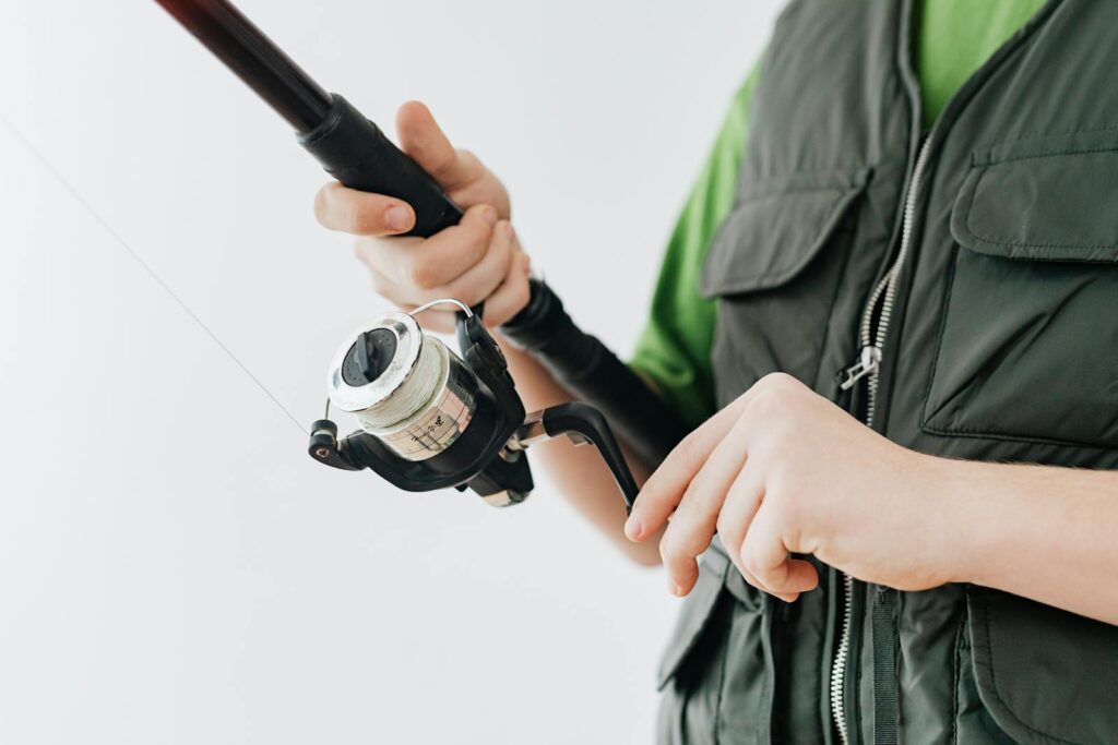 Close-up of a young person adjusting a fishing rod indoors, highlighting a leisure activity.