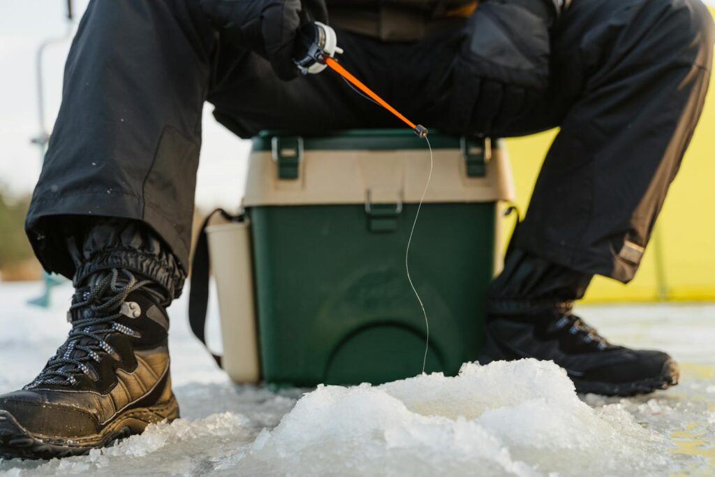 Person ice fishing on a frozen lake in winter, showcasing outdoor activity and gear.