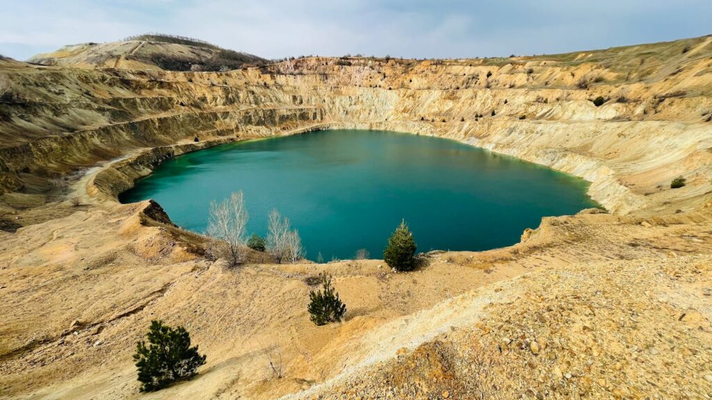 A stunning turquoise lake nestled in an old Nevada mine surrounded by barren hills.