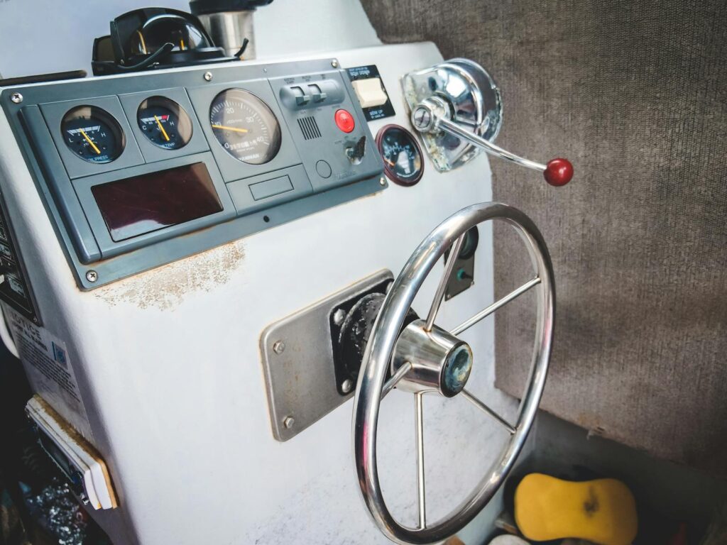 Close-up of a vintage boat steering wheel with control panel, showcasing classic design elements.
