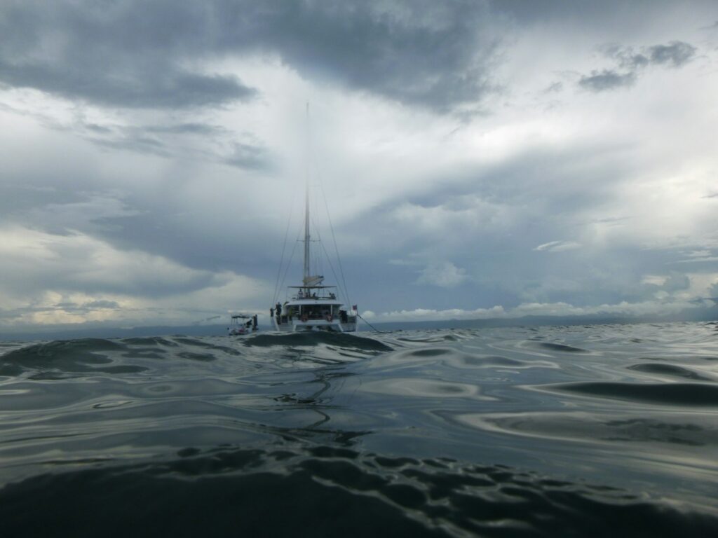 a boat floating on top of a body of water under a cloudy sky