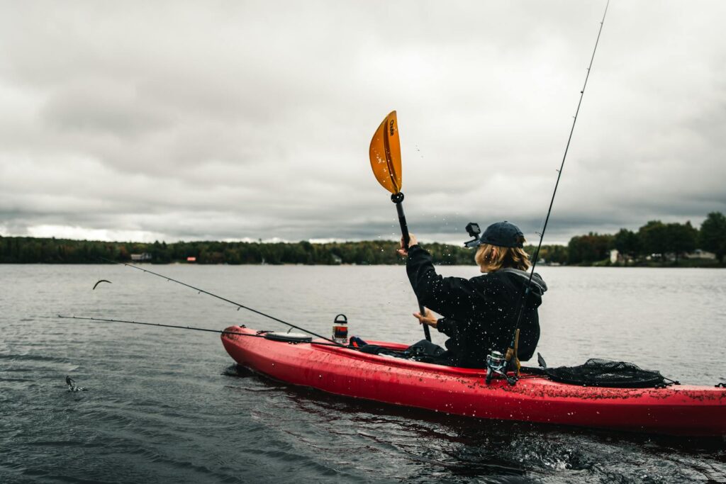 Explore the tranquility of kayaking with a woman paddling on a peaceful lake.