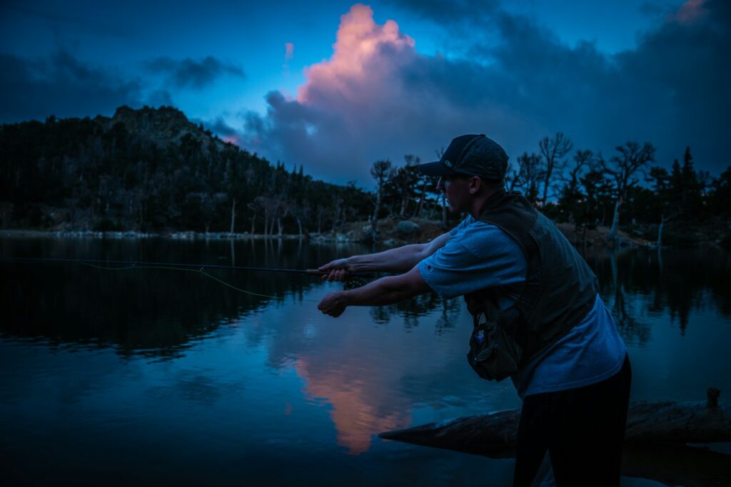 man in blue hoodie standing near lake during daytime