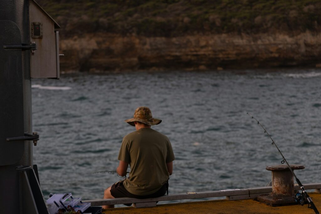 A man sitting on a boat fishing in the water