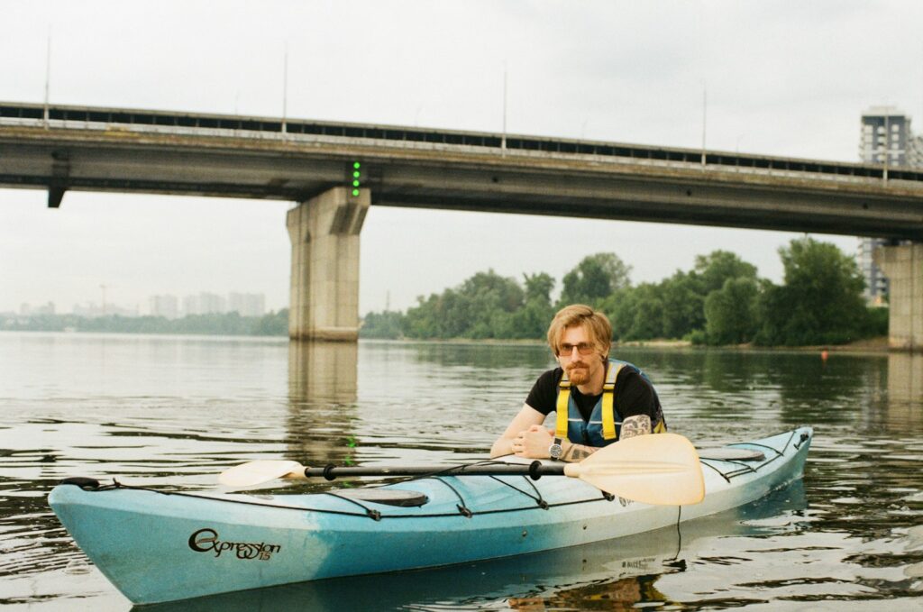 man wearing black shirt sitting on kayak