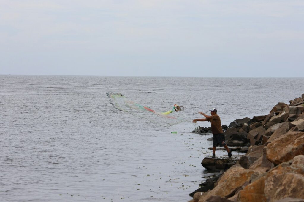 A man standing on a rock wall next to a body of water