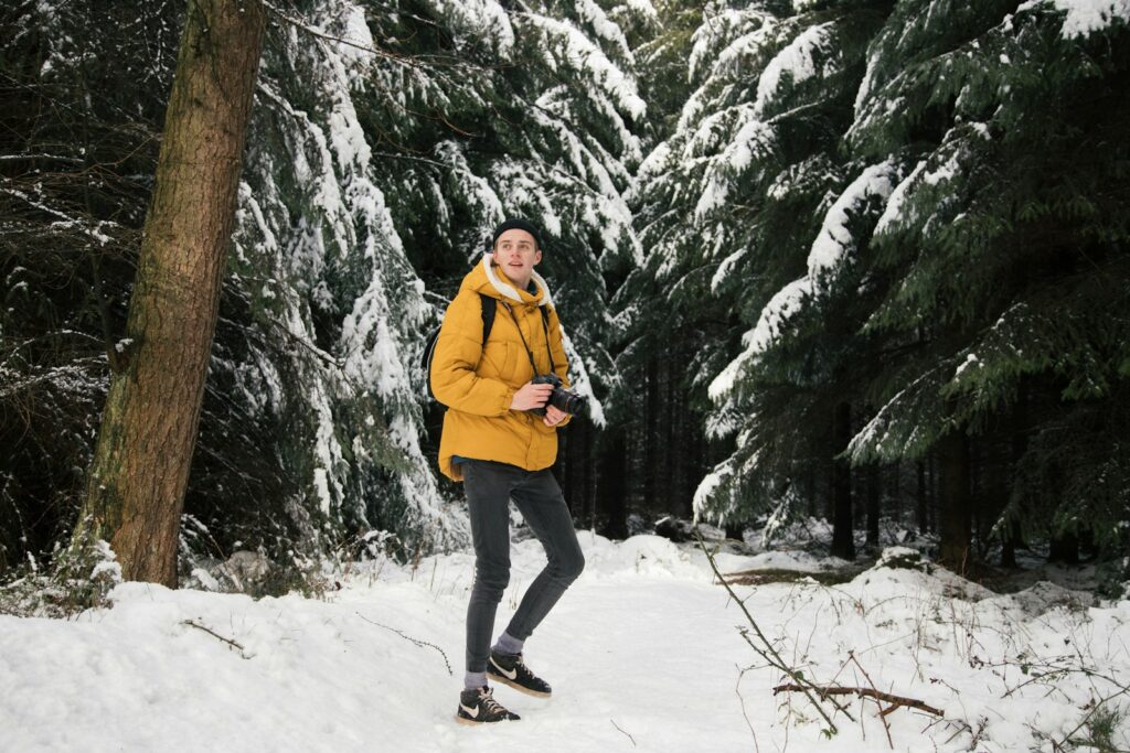man standing near trees holding camera