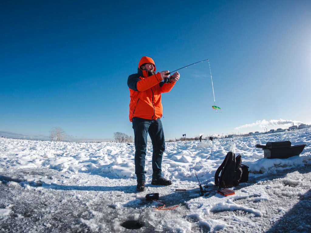 A man is ice fishing on a frozen lake.