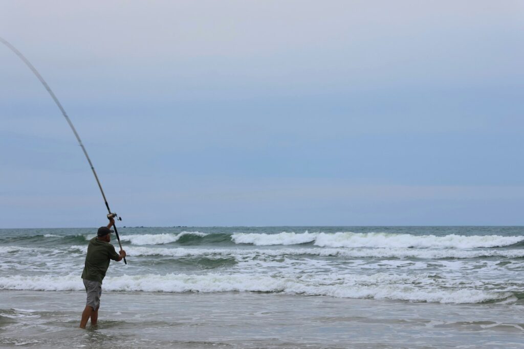 A man standing in the ocean holding a fishing rod