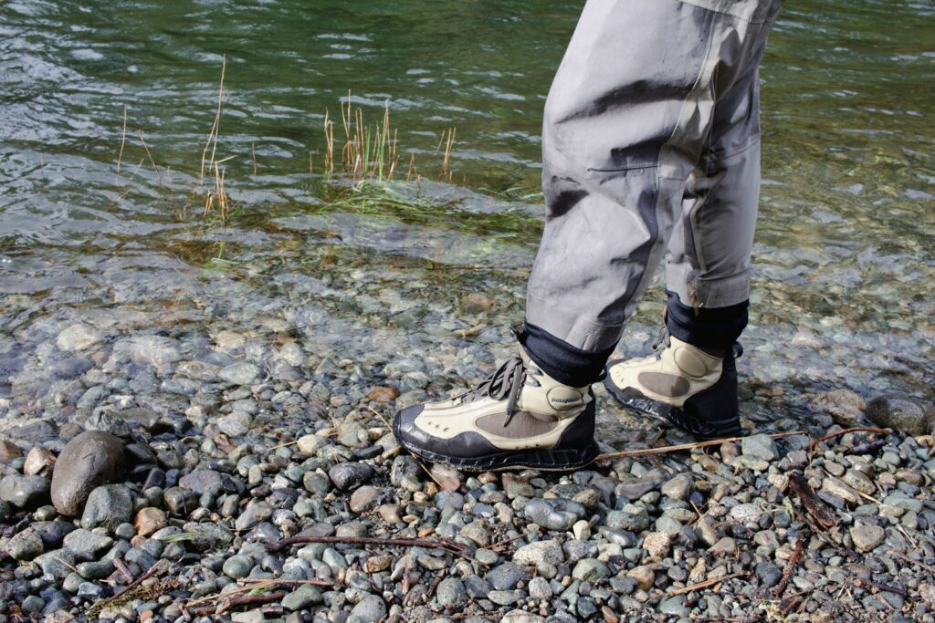 a person standing on a rocky shore next to a river