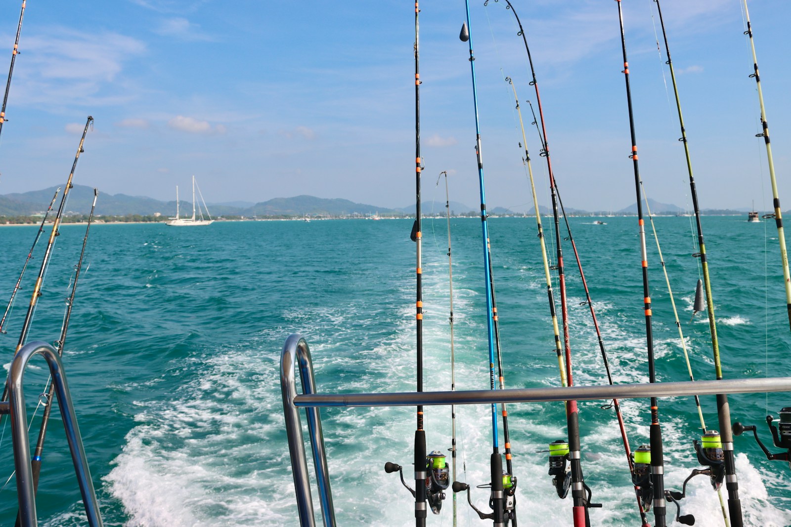 A bunch of fishing rods on a boat in the water.