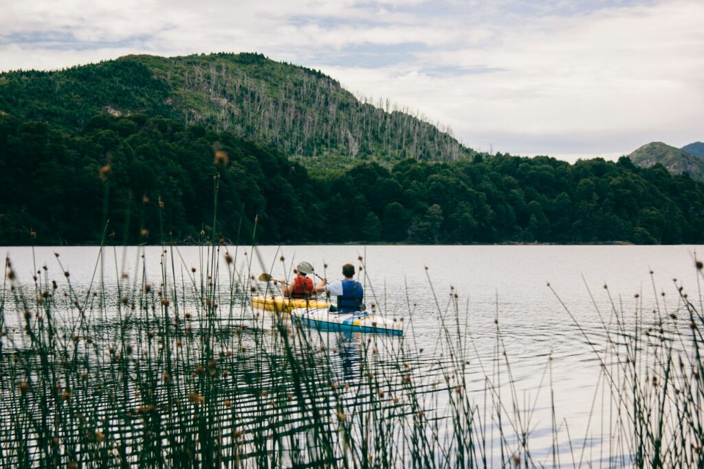 Two person kayaking near mountain.