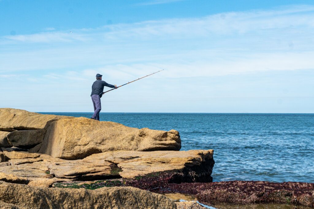 A man standing on top of a rock next to the ocean.