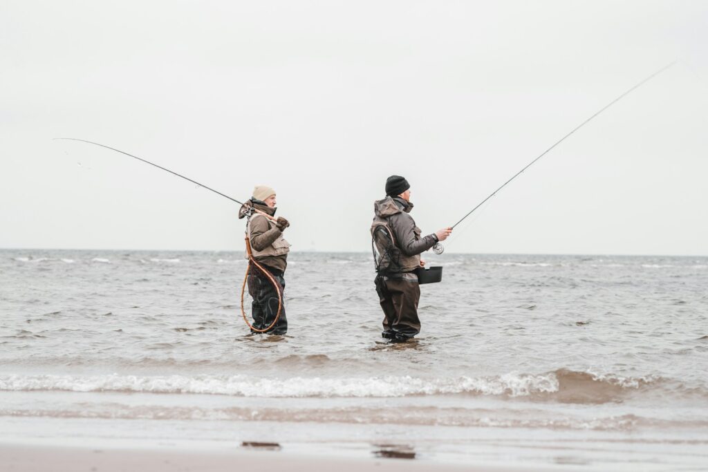 Two people are fishing on sea during daytime.
