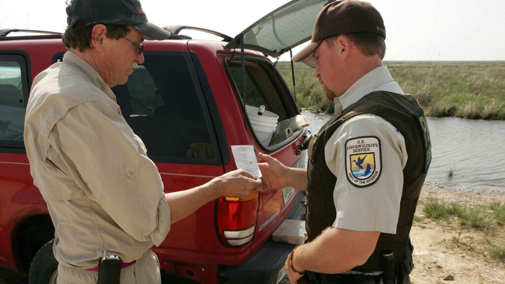 A U.S. Fish and Wildlife Service employee checking a fishing license