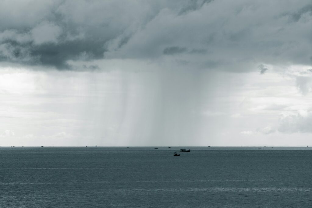A body of water with boats in it and clouds above.