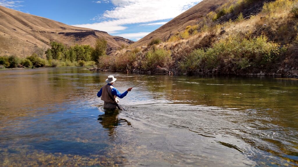 A man wearing a brown hat is fishing on the water.