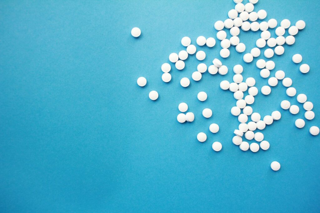 A pile of white pills sitting on top of a blue table.