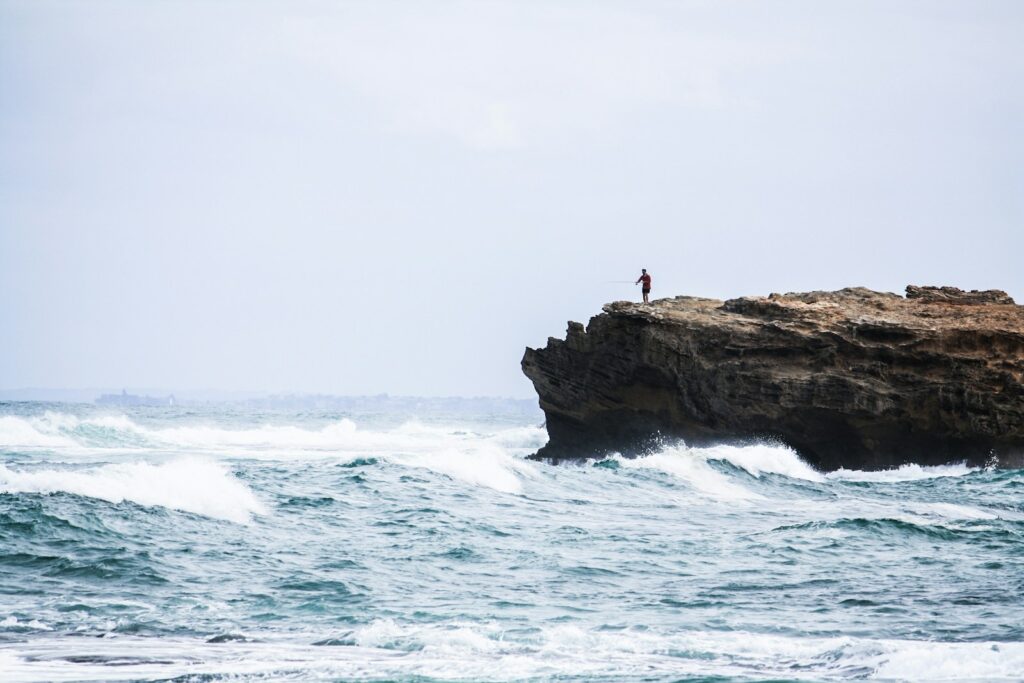 A man standing on rock looking at the sea.