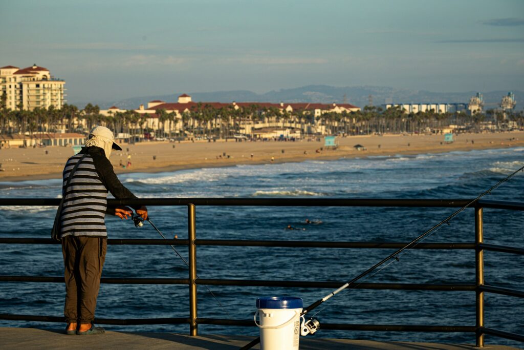 A person fishing on a pier next to the ocean.