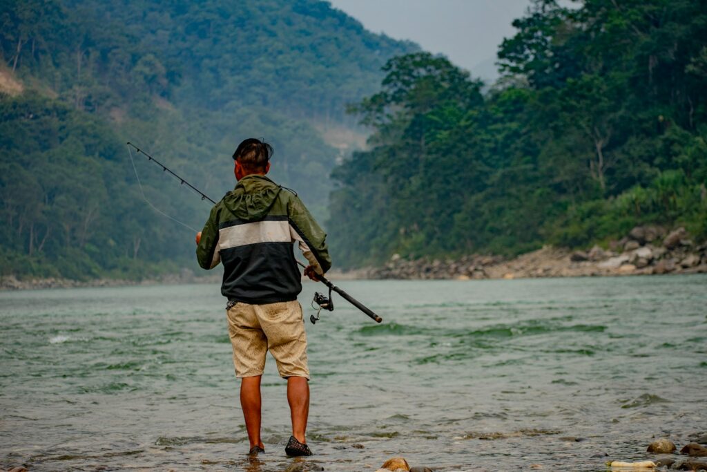 A man standing in the river holding a fishing rod.